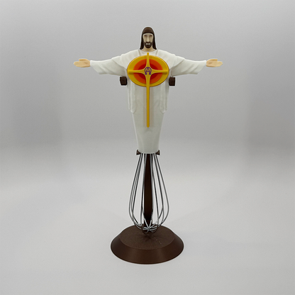 Eggbeater Jesus whisk ornament on the bronze stand, showing the orange starburst cross detail